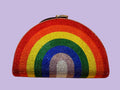 A semi-circular, rainbow-colored rhinestone clutch purse with a silver-tone metal clasp, displayed on a warm beige background.